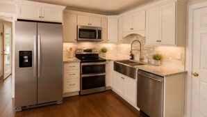 Una cocina con armarios blancos, electrodomésticos de acero inoxidable y encimera de granito.