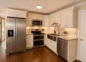 A kitchen with white cabinetry, stainless steel appliances, and a granite countertop. -  Private Sunset Lakefront Getaway  Kayaks, Private Dock & Stunning Views  (Lyman)