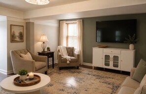 A living room with a sofa, armchair, TV, and a cabinet.