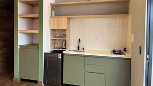 A kitchen with green cabinets, a black dishwasher, a sink, and a stove. - Boreal Glamping (Guatape)