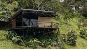 A modern house with a balcony, surrounded by lush greenery. - Boreal Glamping (Guatape)