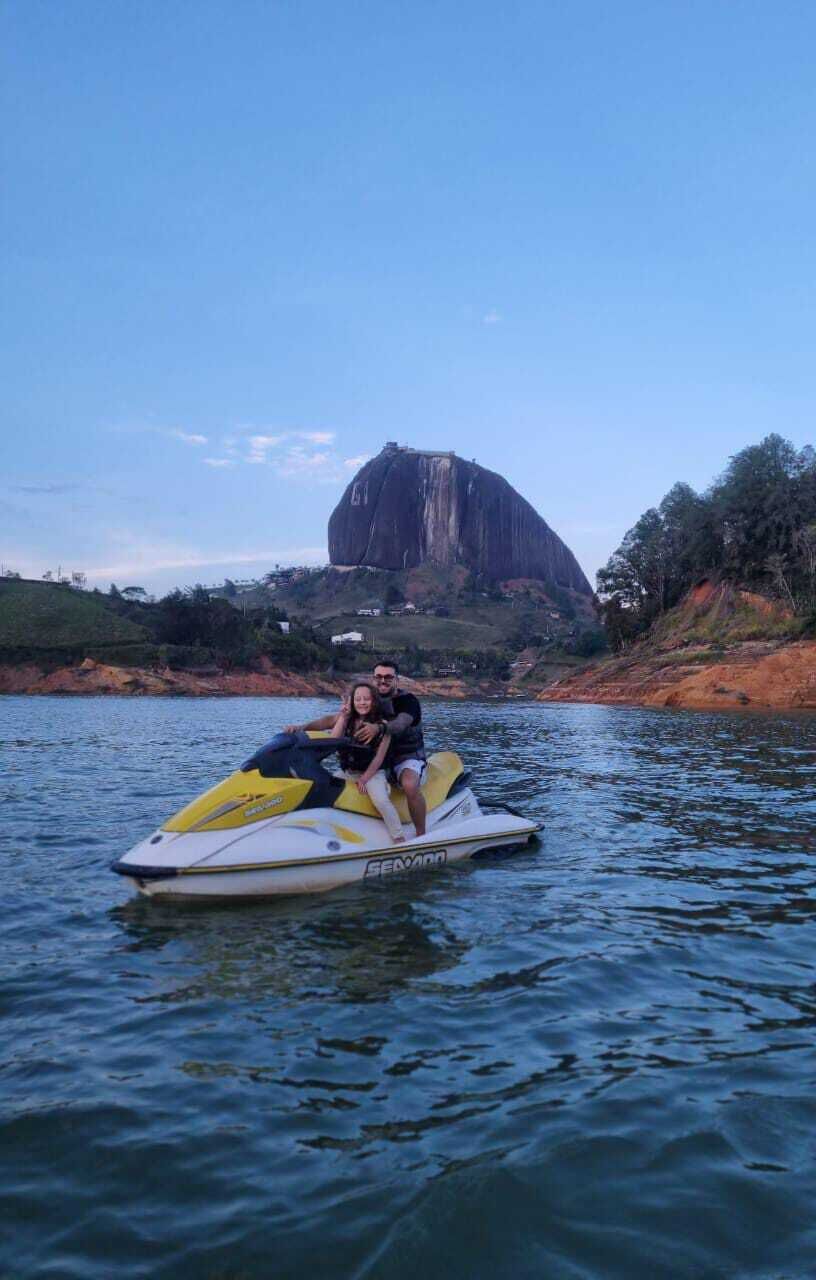 Un jet ski sobre aguas tranquilas, con una gran formación rocosa al fondo.