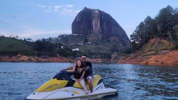 Un jet ski sobre aguas tranquilas, con una gran formación rocosa al fondo.