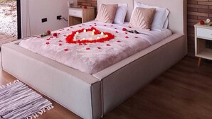 A modern bedroom with a brick wall, a bed with rose petals and a heart-shaped arrangement, and red balloons. - Boreal Glamping (Guatape)