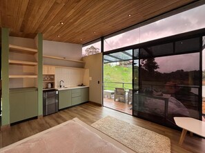 A modern kitchen with a large sliding glass door leading to an outdoor patio area. - Boreal Glamping (Guatape)