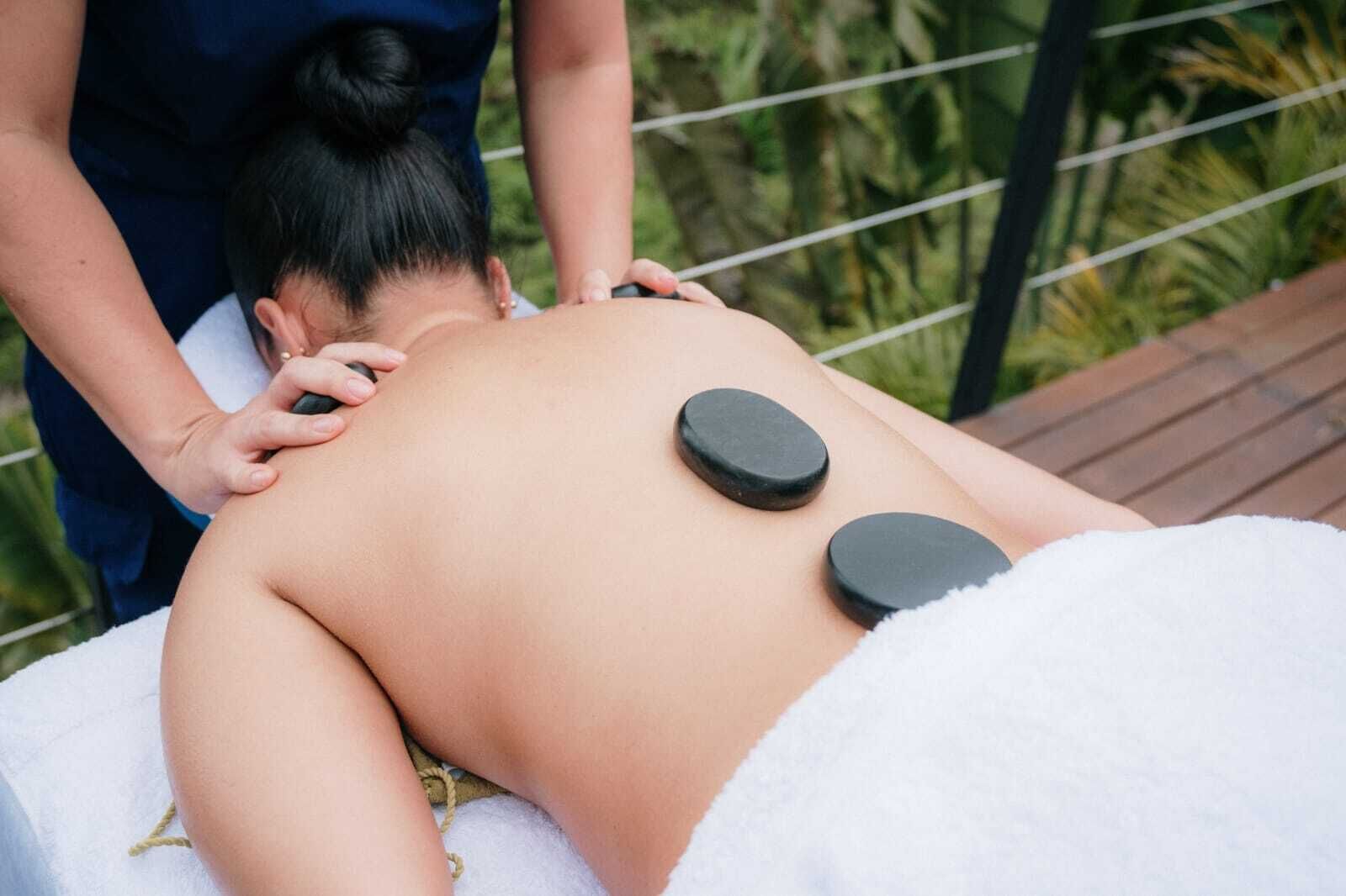 A massage therapy session with a person lying on a treatment table, receiving back and shoulder massages.