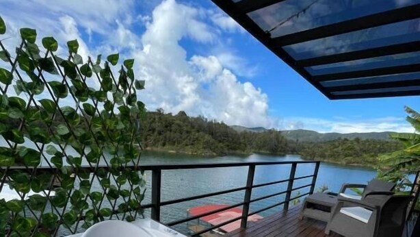 A hot tub on a wooden deck with a view of a lake and mountains. - Boreal Glamping (Guatape)