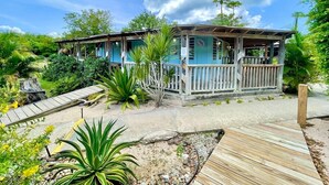 Um edifício de dois andares com deck de madeira, cercado por vegetação tropical.