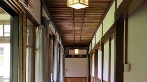 A corridor with wooden flooring, large windows, and a hanging light fixture. - Nuruyu Onsen Sato Ryokan (Kurihara)