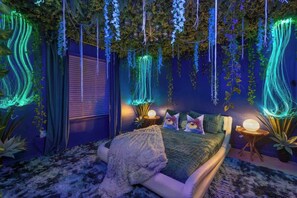 Ein Schlafzimmer mit einem Bett, Nachttischen und einer Wand, an der Kletterpflanzen und Lichter hängen.