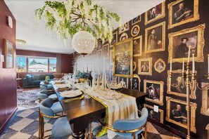 A dining room with a long table set for a meal, surrounded by chairs, with a chandelier above. - Game Rooms, Hot Tub & Fire Pit (Arvada)