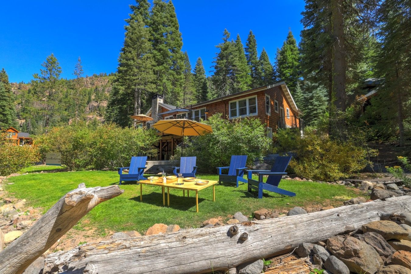 A lodge with a dining area, outdoor seating, and a view of the surrounding forest.