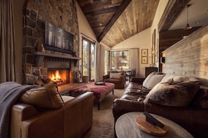 Ein gemütliches Wohnzimmer mit Kamin aus Stein, Ledersofas und Holzboden.
