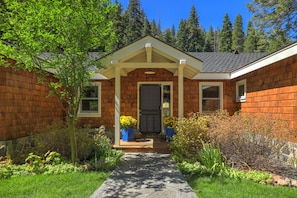 A two-story house with a covered porch, a front door, and a pathway leading to the entrance.