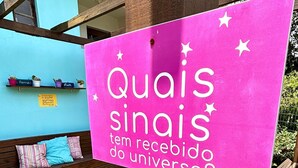 A pink sign with white text on a wooden post. - Pousada Astral (Imbituba)