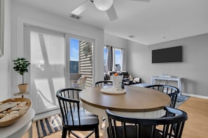 Een moderne eetruimte met een ronde tafel, zwarte stoelen en een plafondventilator.