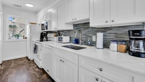 Una cucina moderna con mobili bianchi, lavello in acciaio inossidabile, macchina da caffè e forno a microonde.
