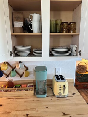 Una cucina con una macchina da caffè, un tostapane e diverse tazze e piatti.