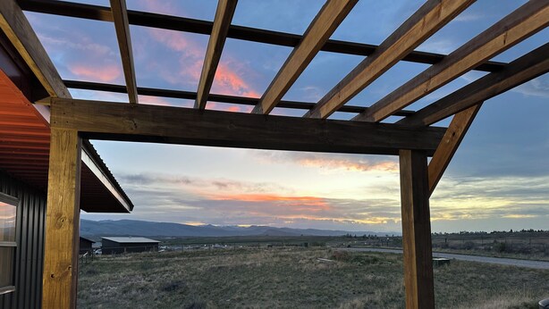 A wooden pergola structure with a view of a rural landscape and mountains in the distance. - Cottontail Cottage-Peaceful 1-bedroom cottage with AC in charming Lander (Lander)