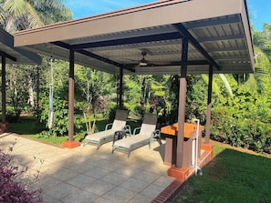 A covered outdoor seating area with two lounge chairs and a table, surrounded by lush greenery. - Apartment for 4 travellers in a hotel (Ciudad Cortés)