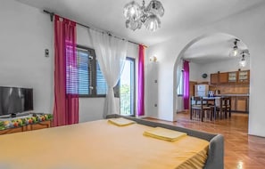 Hotellihuone, jossa on sänky, televisio, keittotila ja ruokapöytä.