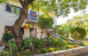 A residential building with a balcony, potted plants, and a stone wall. - Cozy apartment in Klenovica with house sea view (Klenovica)
