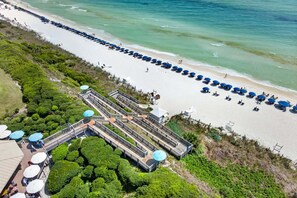 An aerial view of a beach resort with a long promenade, beach umbrellas, and a boardwalk leading to a building with a dome roof. - High Pointe 3433 — 30A Gulf View Escape w/ Pool & Beach Access (Seacrest Beach)