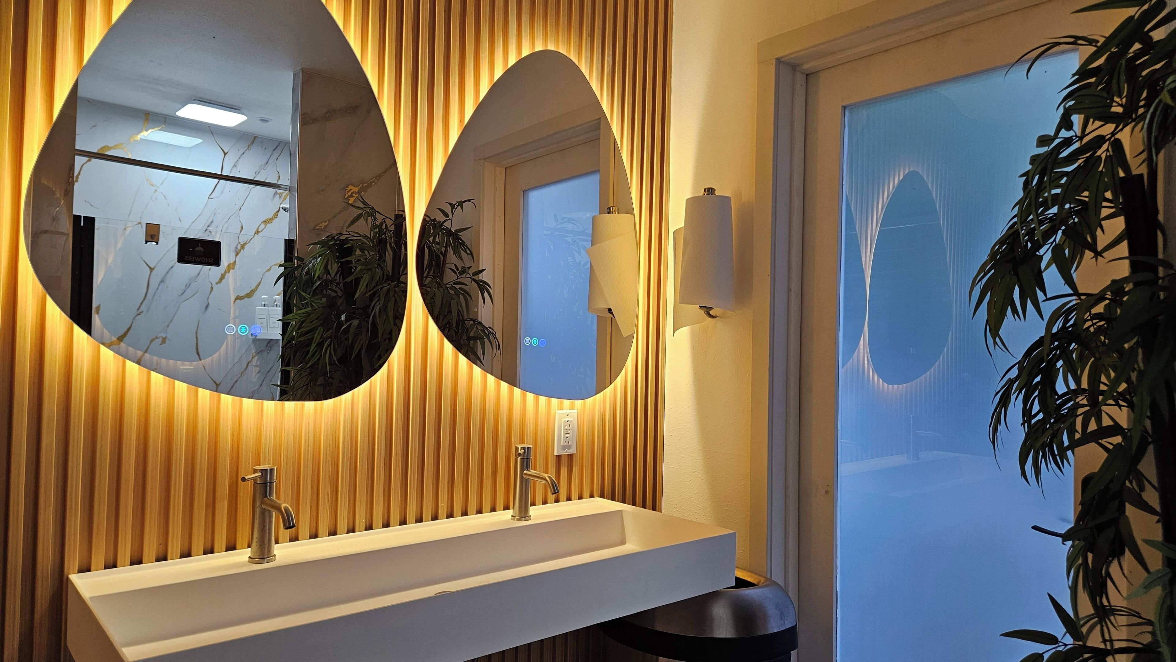 Ein Badezimmer mit Waschtisch, zwei Spiegeln, einem Waschbecken und einer Tür.