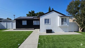 Une maison à deux étages, avec une façade blanche, un garage noir et une pelouse bien entretenue.
