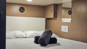 Une chambre d’hôtel équipée d’un lit, d’un miroir fixé au mur, d’une prise de courant et d’une bouche d’aération.