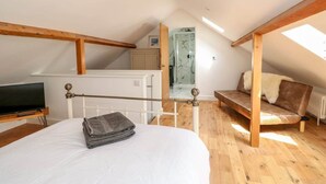 A bedroom with a bed, a TV, a wooden bench, and a skylight.