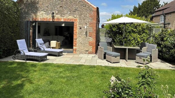 A stone building with a patio area, outdoor seating, and a covered section.