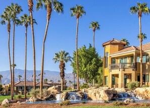 Un resort con varias construcciones, palmeras y una cascada.