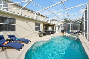 Area piscina con lettini, barbecue e patio coperto.