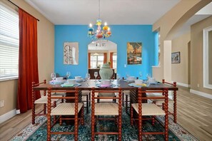 Ein Esszimmer mit Holztisch, gedeckt für sechs Personen, umgeben von Stühlen, einer Chandelierleuchtre und Kunstwerken an den Wänden.