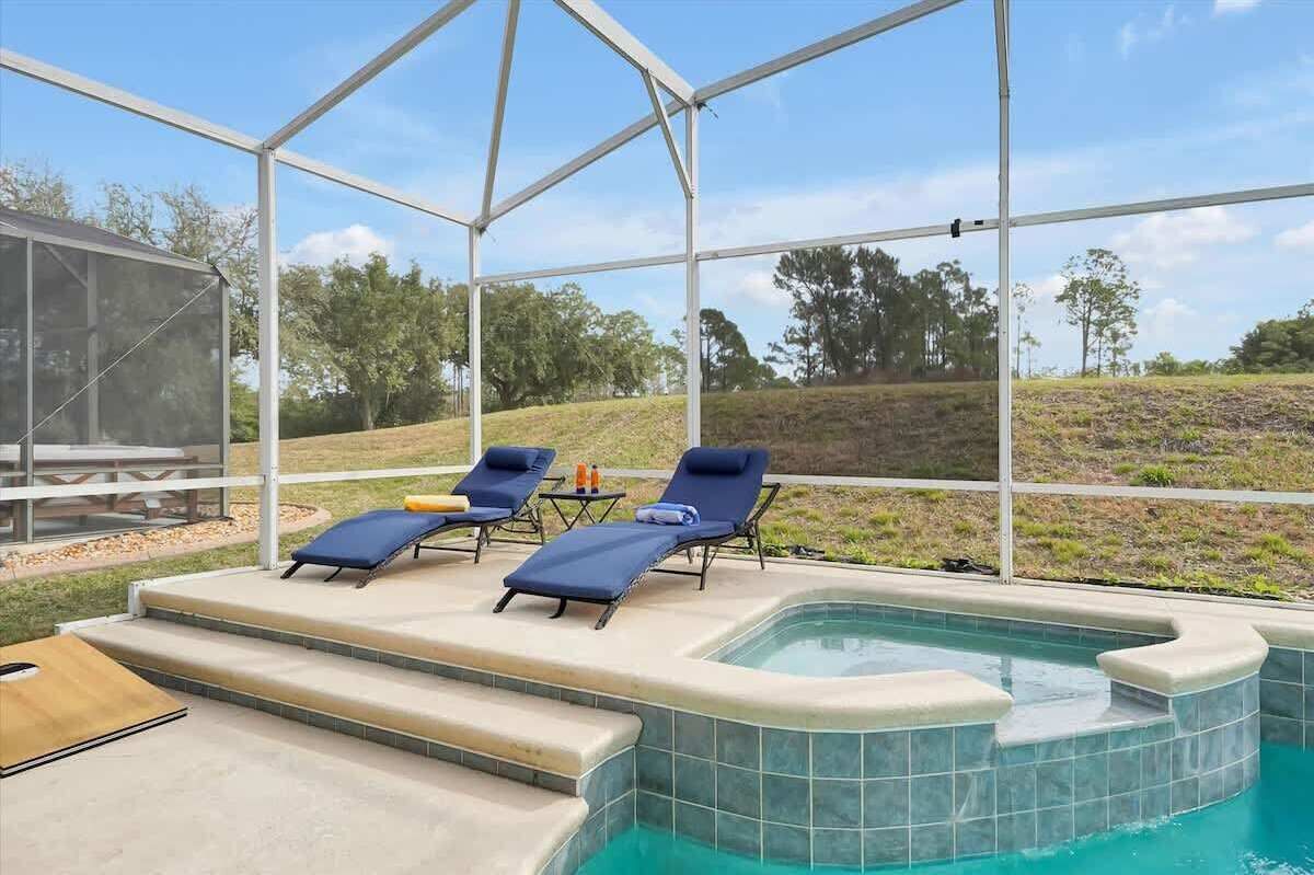 A covered outdoor swimming pool with lounge chairs and a picnic table.
