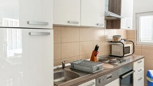Cozinha moderna com armários brancos, uma pia de aço inoxidável, micro-ondas e forno embutido.