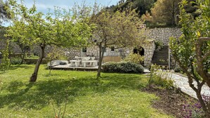 Um edifício de pedra com área de estar ao ar livre, rodeado por vegetação e uma escadaria de pedra.