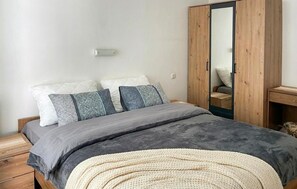 Ein Schlafzimmer mit Bett, Kissen, einem Nachttisch und einem Kleiderschrank.