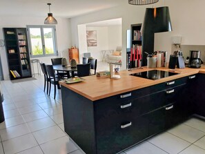 Eine moderne Küche mit Kochinsel, schwarzen Schränken und einem Essbereich mit Stühlen und Tisch.