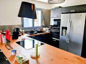 Eine moderne Küche mit Kochinsel, Edelstahlgeräten und einem Fenster für natürliches Licht.