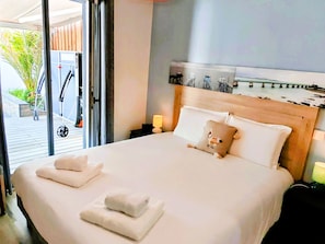Ein Hotelzimmer mit Bett, Nachttisch, Lampe und Blick ins Freie.
