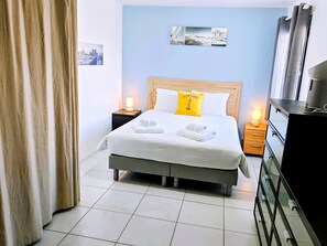 Ein Hotelzimmer mit Bett, Nachttischen, einem Schminktisch und einem Wandbild.