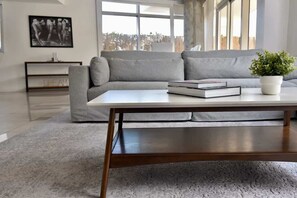 Ein modernes Wohnzimmer mit einem grauen Sofa, einem Holztisch und einer Zimmerpflanze.