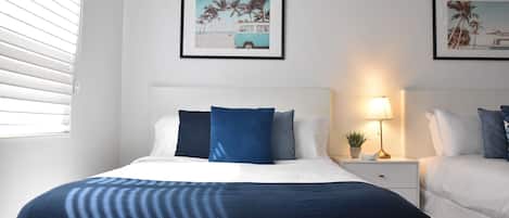 A hotel room with a bed, a bedside table with a lamp, and two framed pictures on the wall.