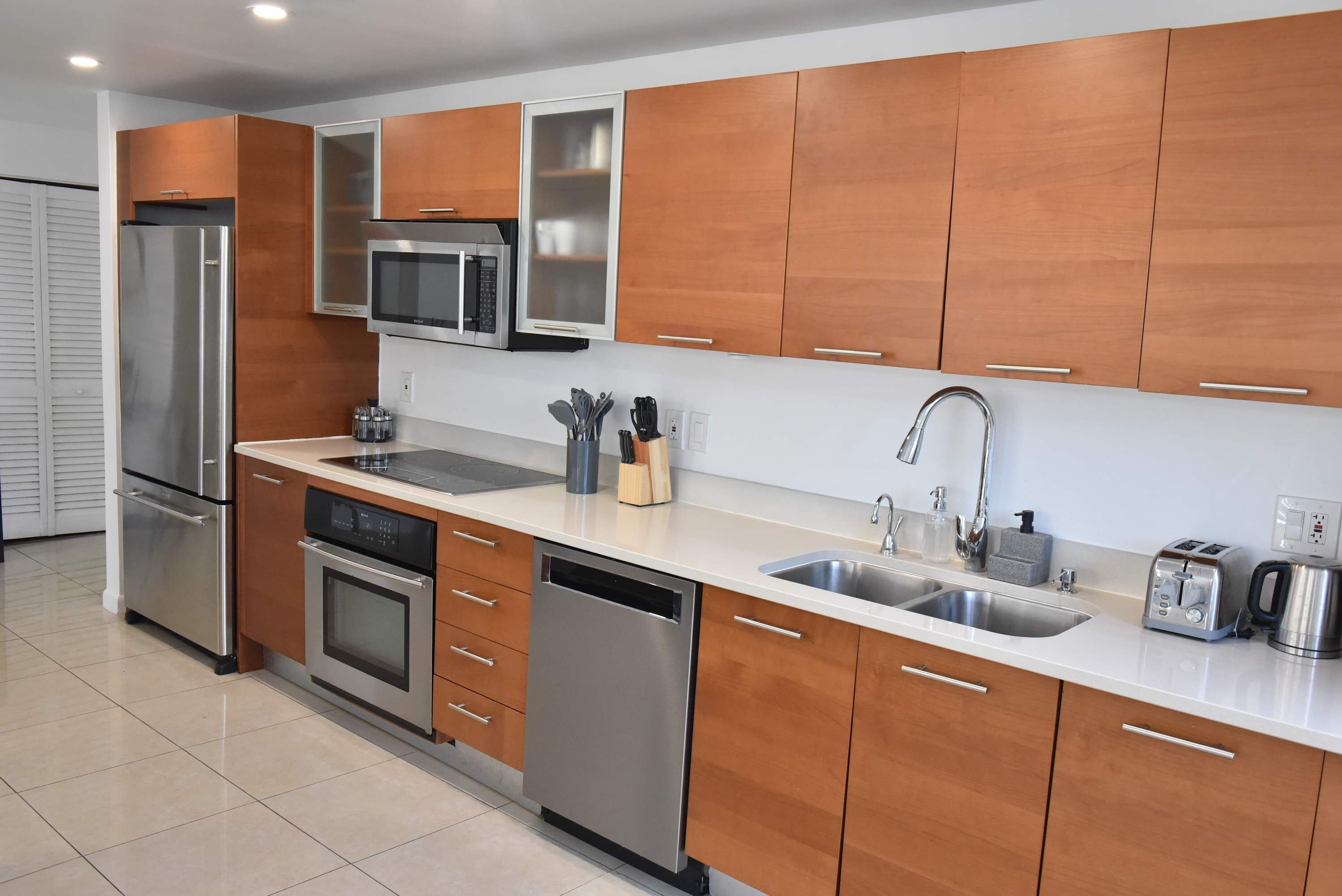 Una cocina moderna con electrodomésticos de acero inoxidable, armarios de madera y un lavamanos doble.