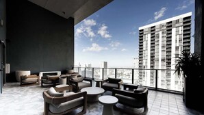 Un moderno salón con sofás, una mesa de centro y un amplio ventanal con vistas a un paisaje urbano.