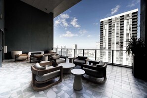 Ein stilvoller Lounge-Bereich mit Sofas, einem Couchtisch und einem großen Fenster mit Blick auf die Skyline der Stadt.