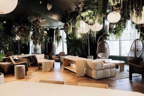 Ein stilvoller Lounge-Bereich mit Sitzmöglichkeiten, hängenden Pflanzen und großen Fenstern.