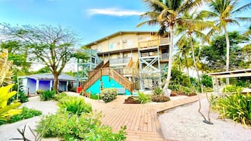 A resort with a wooden deck, palm trees, and a building with multiple balconies.